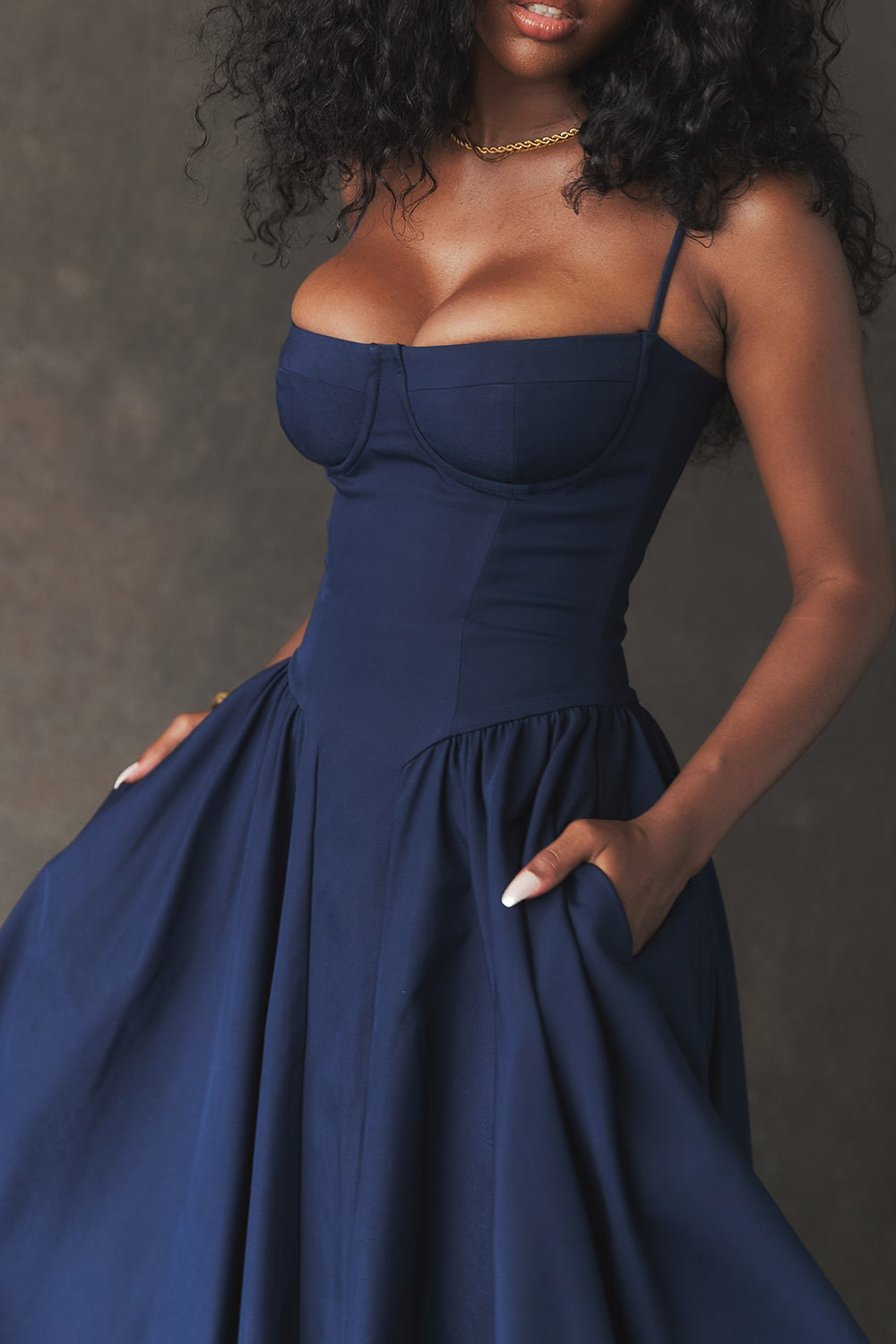 Woman wearing a Navy blue dress against a neutral background