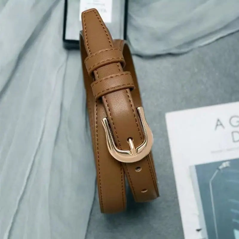 Brown Coffee leather belt with gold buckle on a gray surface