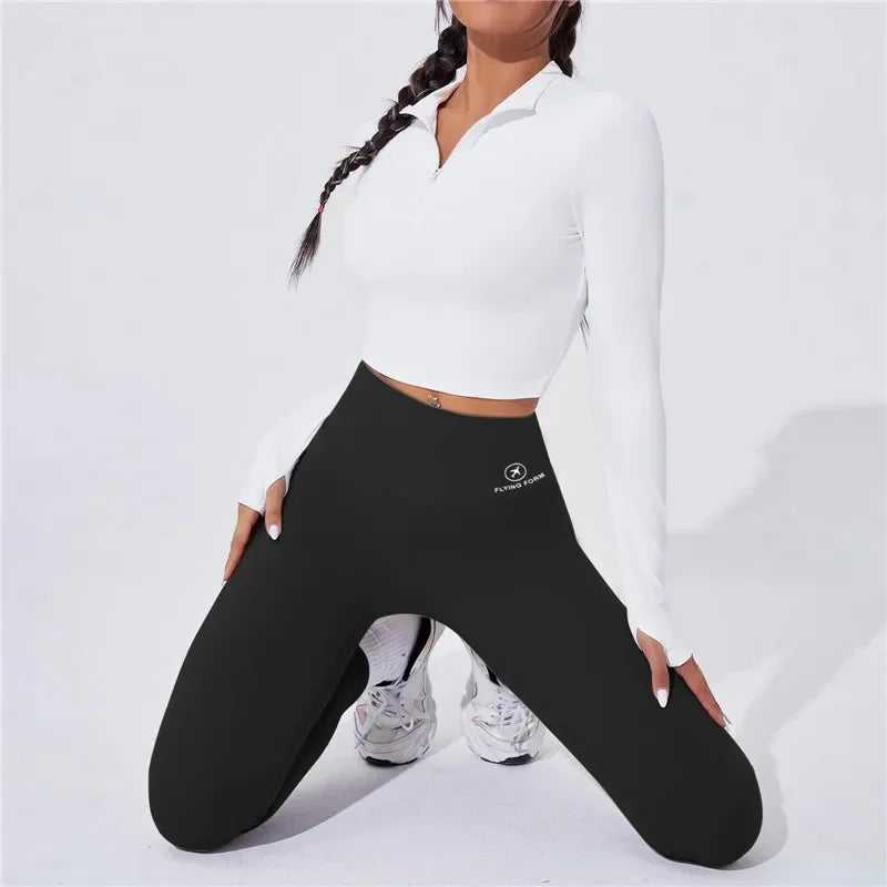 Person wearing Onyx leggings with a logo and a white long-sleeve top on a light gray background