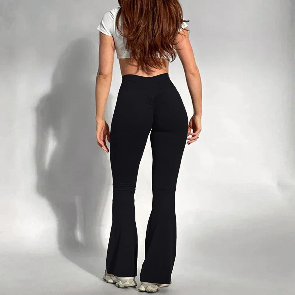 Person wearing Onyx black flared pants and a white top on a plain background